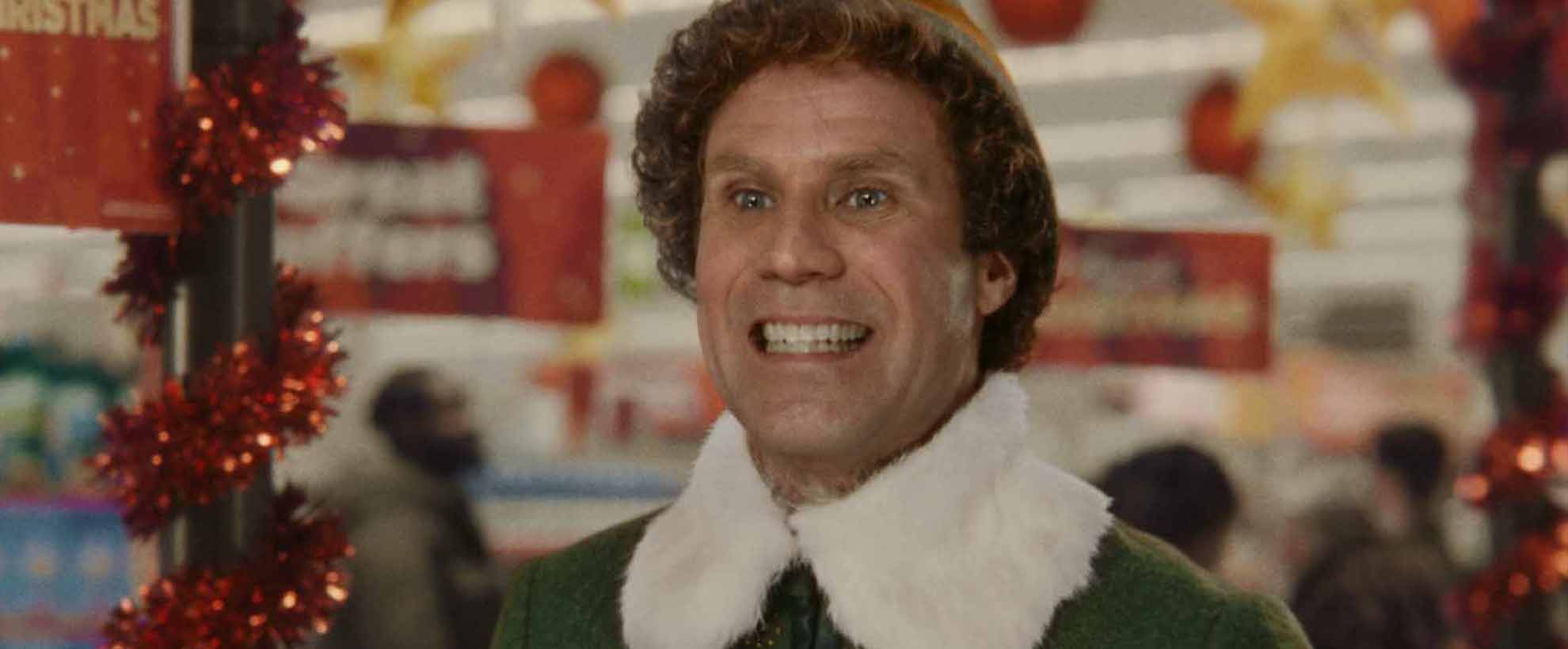 Will Ferrell as Buddy the Elf stands grinning