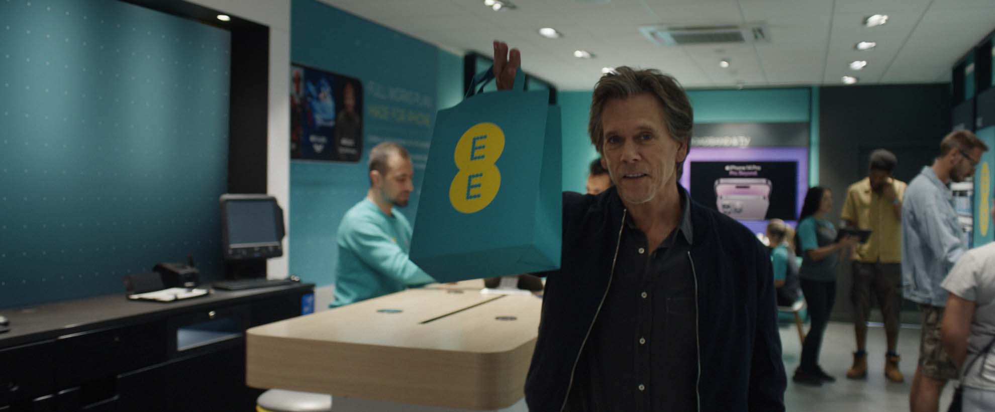 Actor Kevin Bacon holds an EE branded shopping bag
