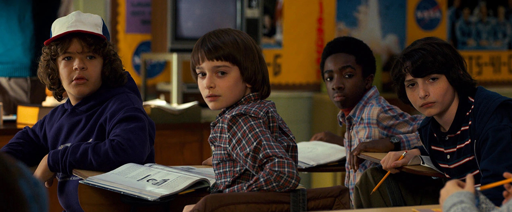 The four young boys in Stranger Things sitting in a classroom, turning to look behind them