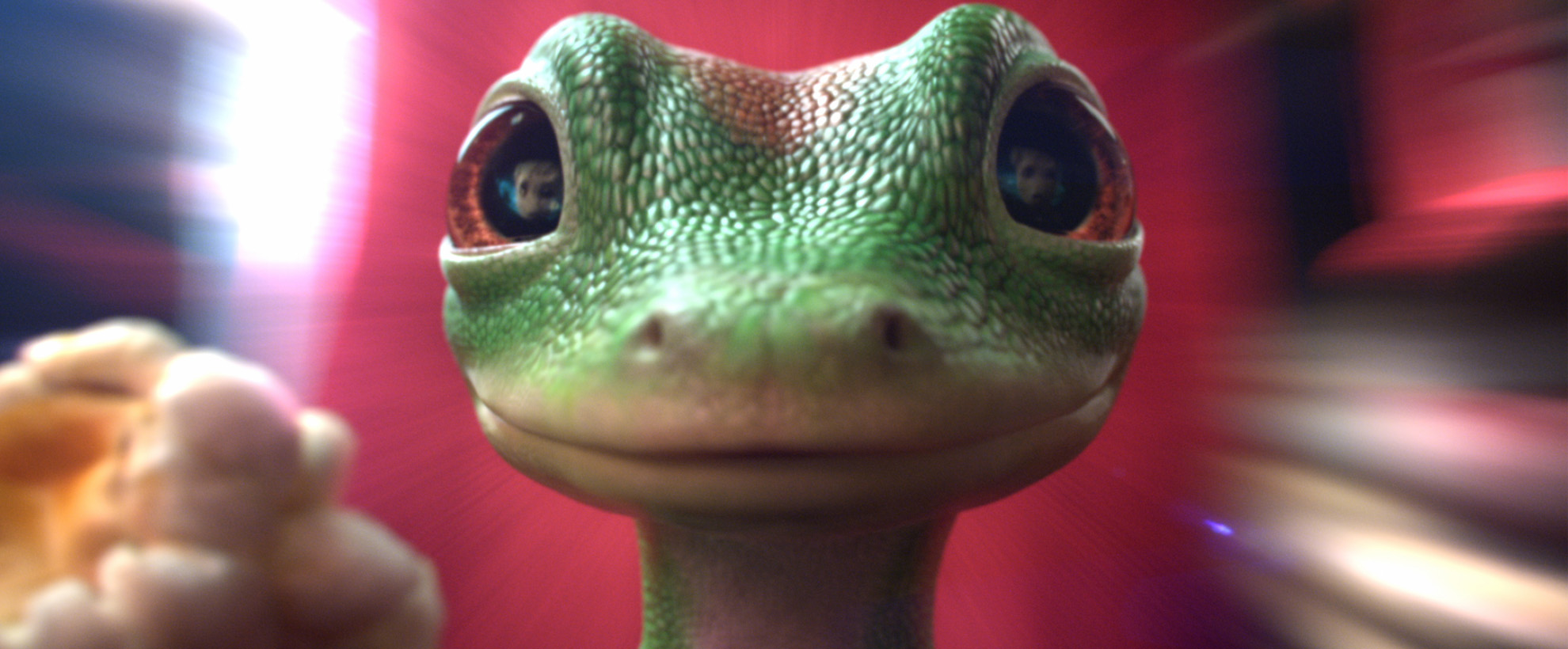 The GEICO gecko stood facing us with a motion blurred red background.