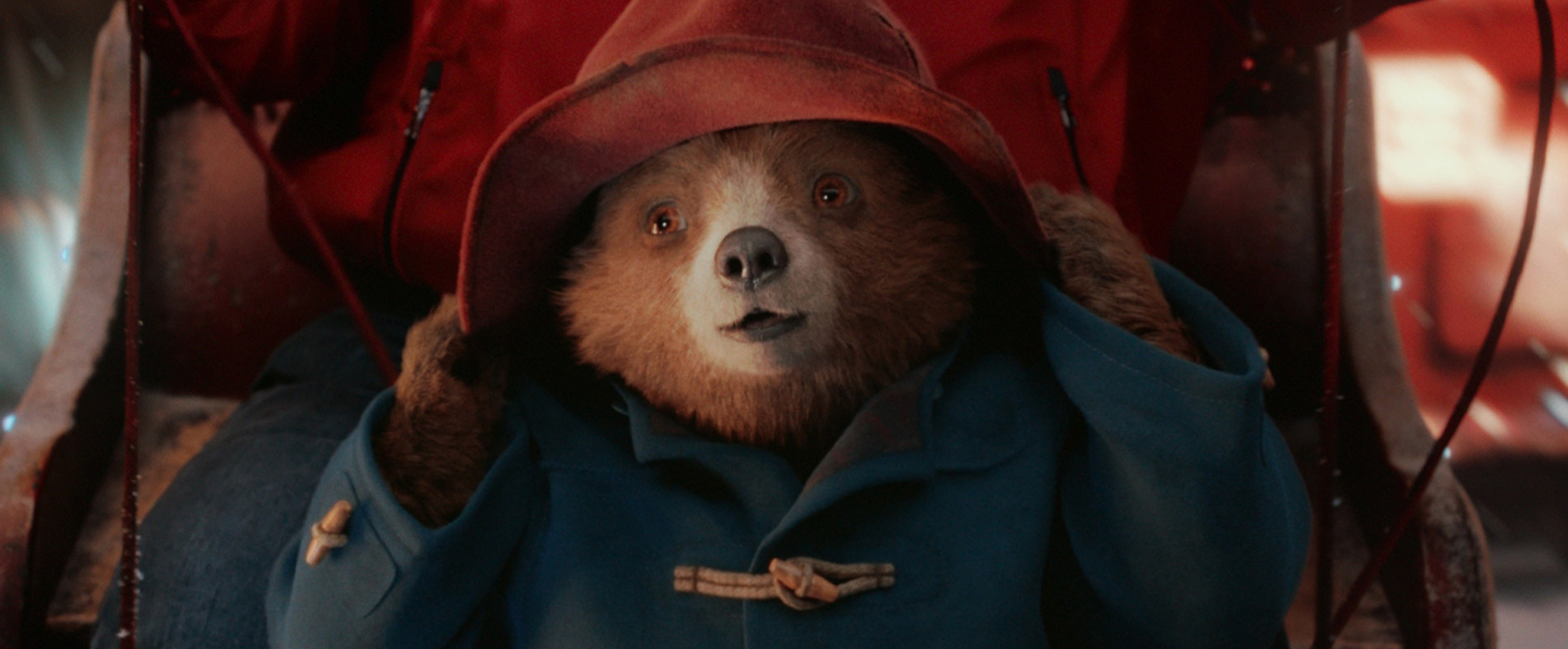Paddington the bear wearing a red rain hat and blue coat