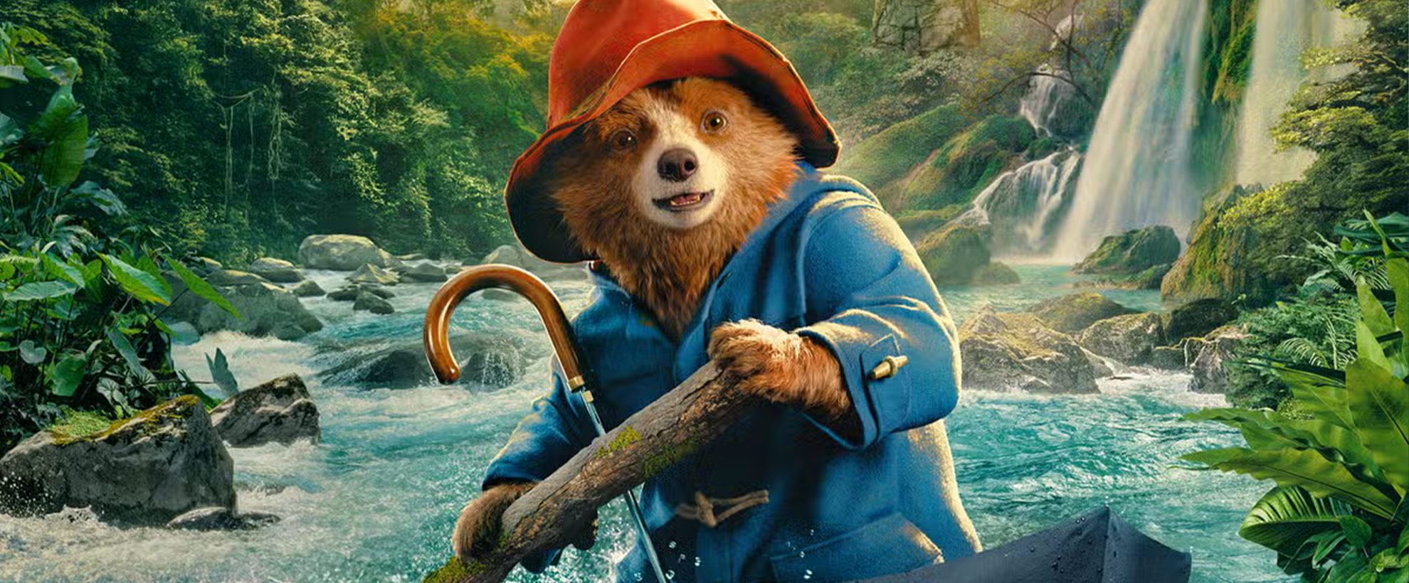 Paddington sits in an upturned umbrella, using it as a boat to sail down jungle rapids