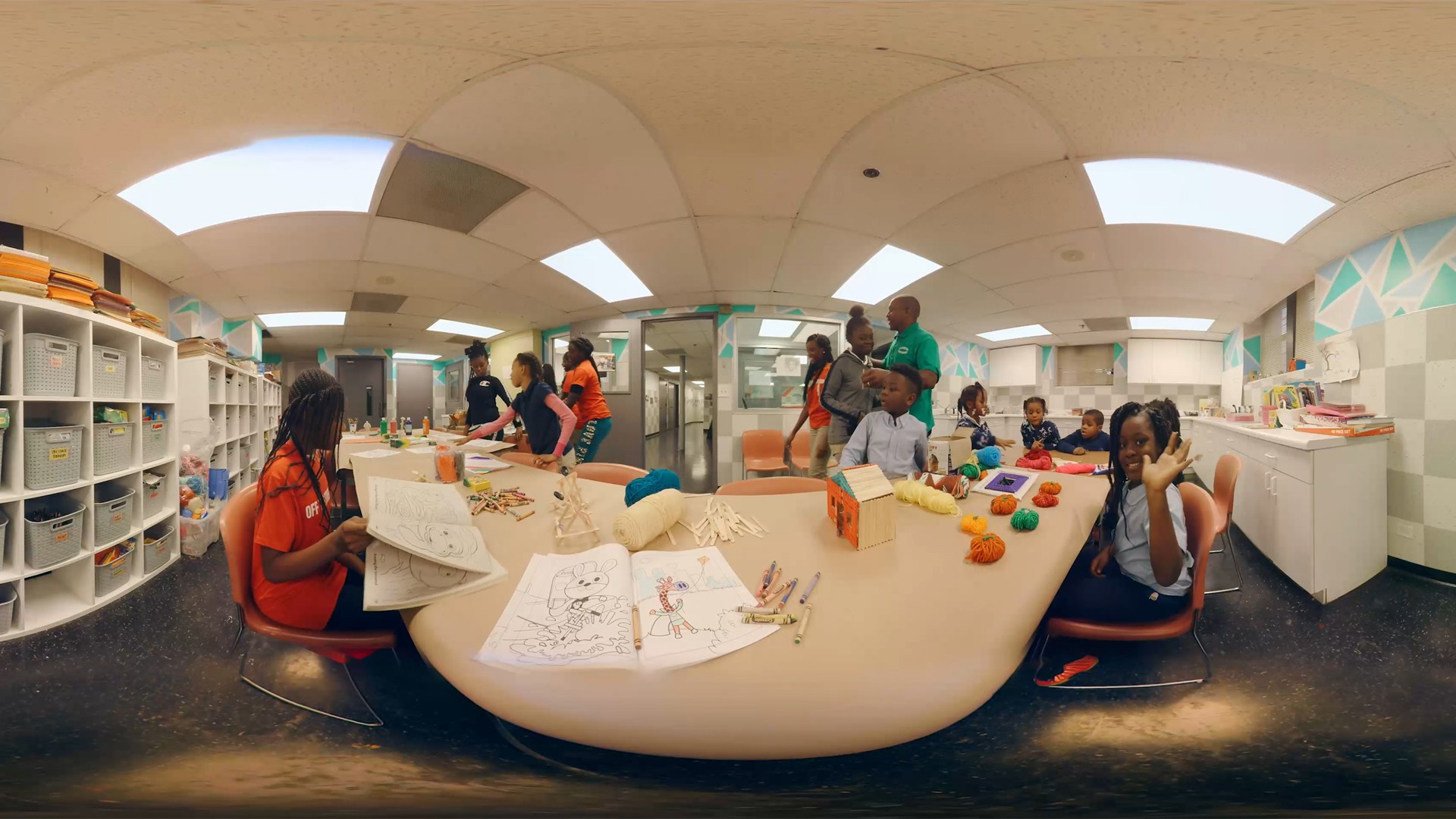 A VR shot of the interior of the Off The Street Club, little girl making drawing, supervisor watches