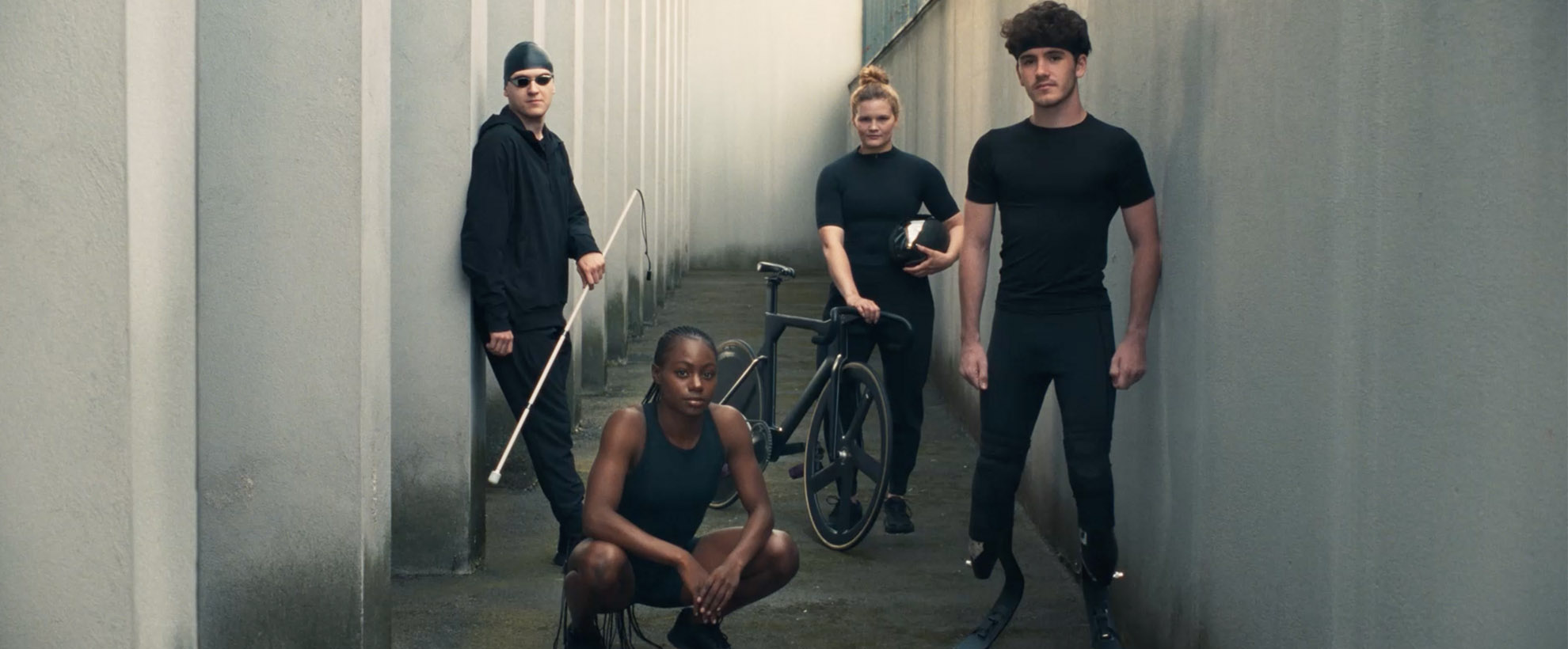 Five athletes, some disabled and some not, stand while wearing all black