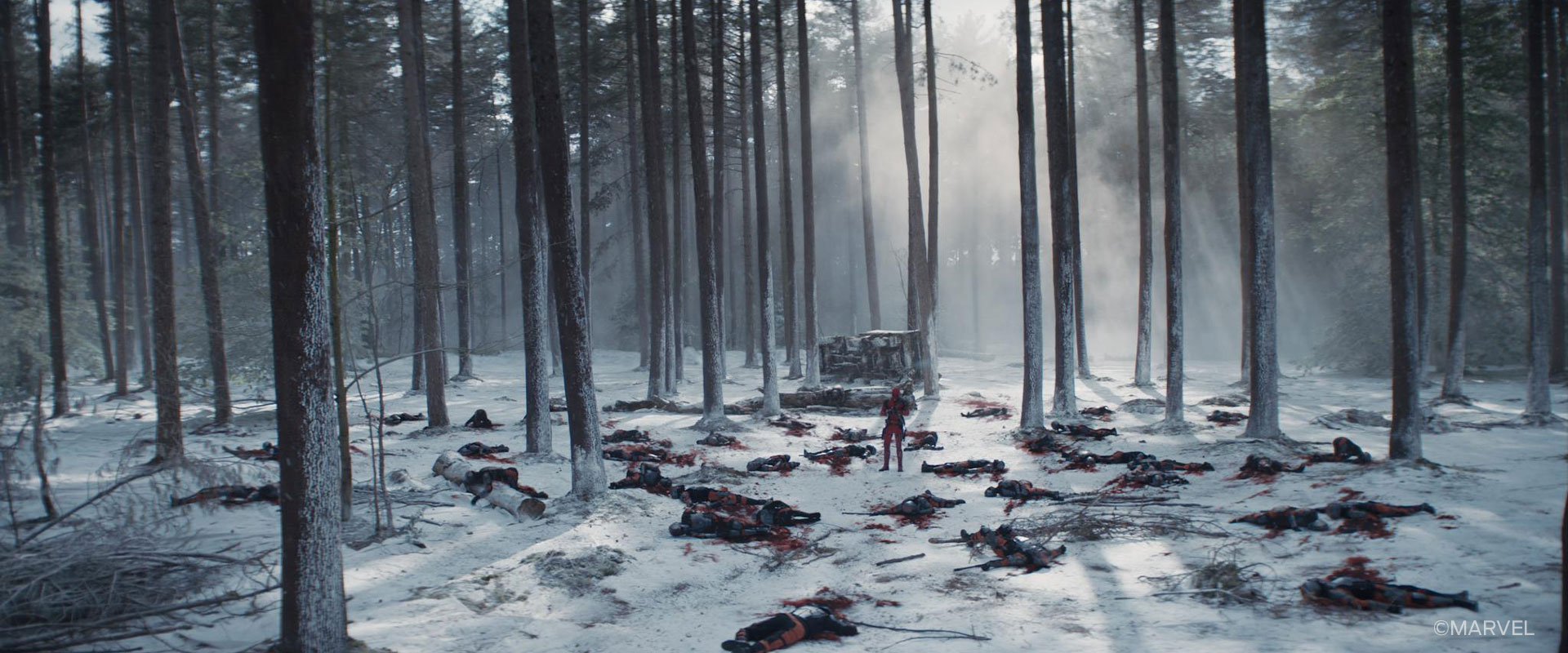 A shot from the opening sequence of Deadpool and Wolverine - Deadpool stands in a snowy forest surrounded by murdered TVA agents