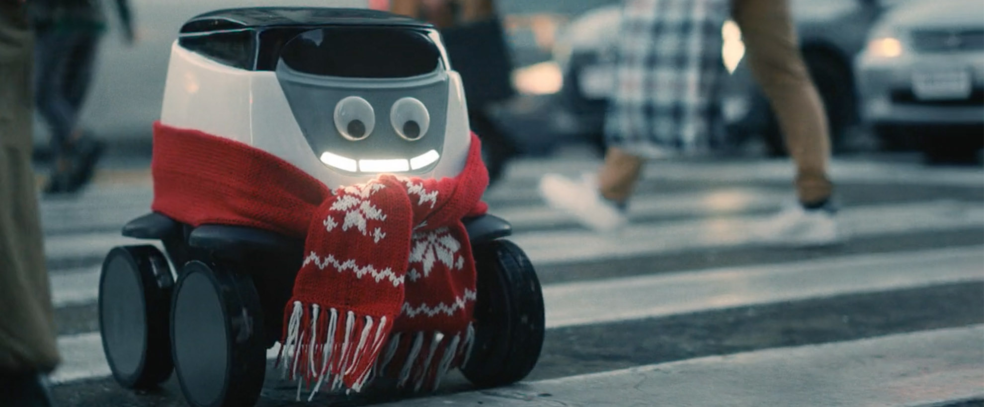 A roboto smiles at is crosses a cross walk with a holiday scarf on 