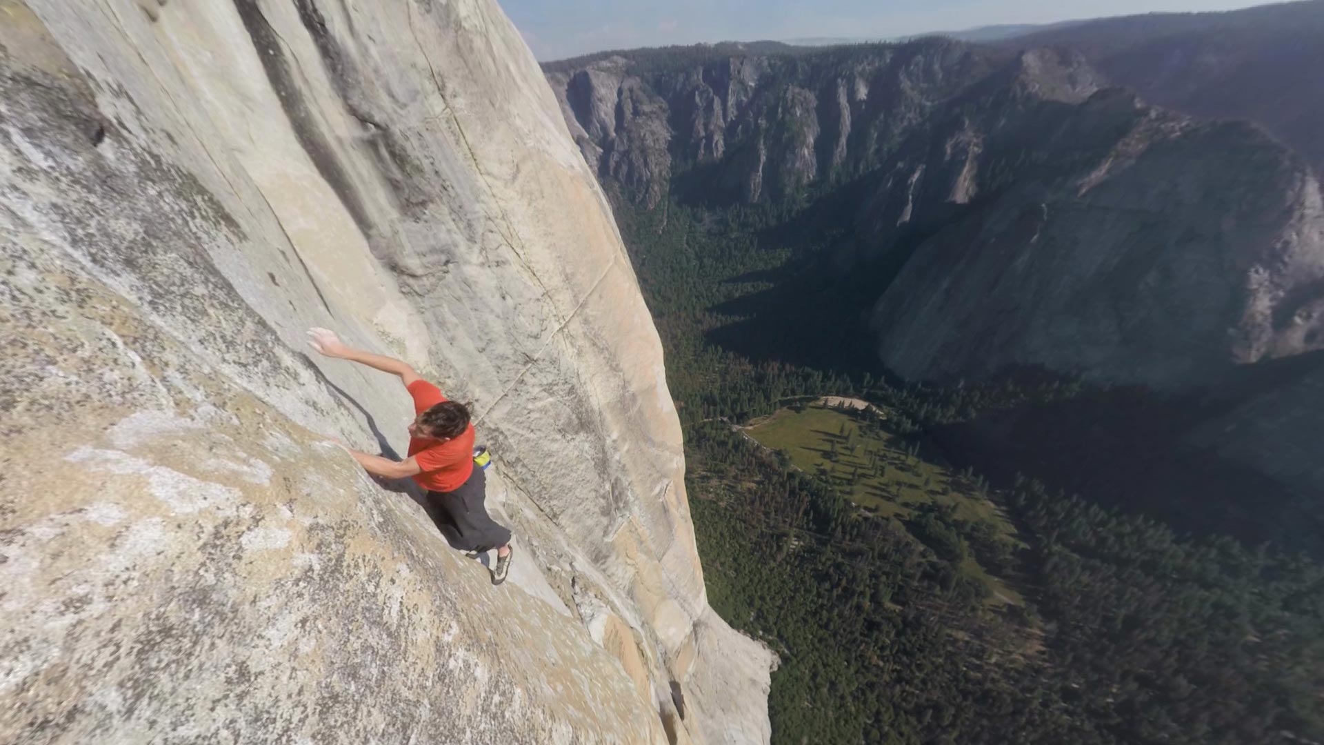 A man hangs on the edge of a large cliff