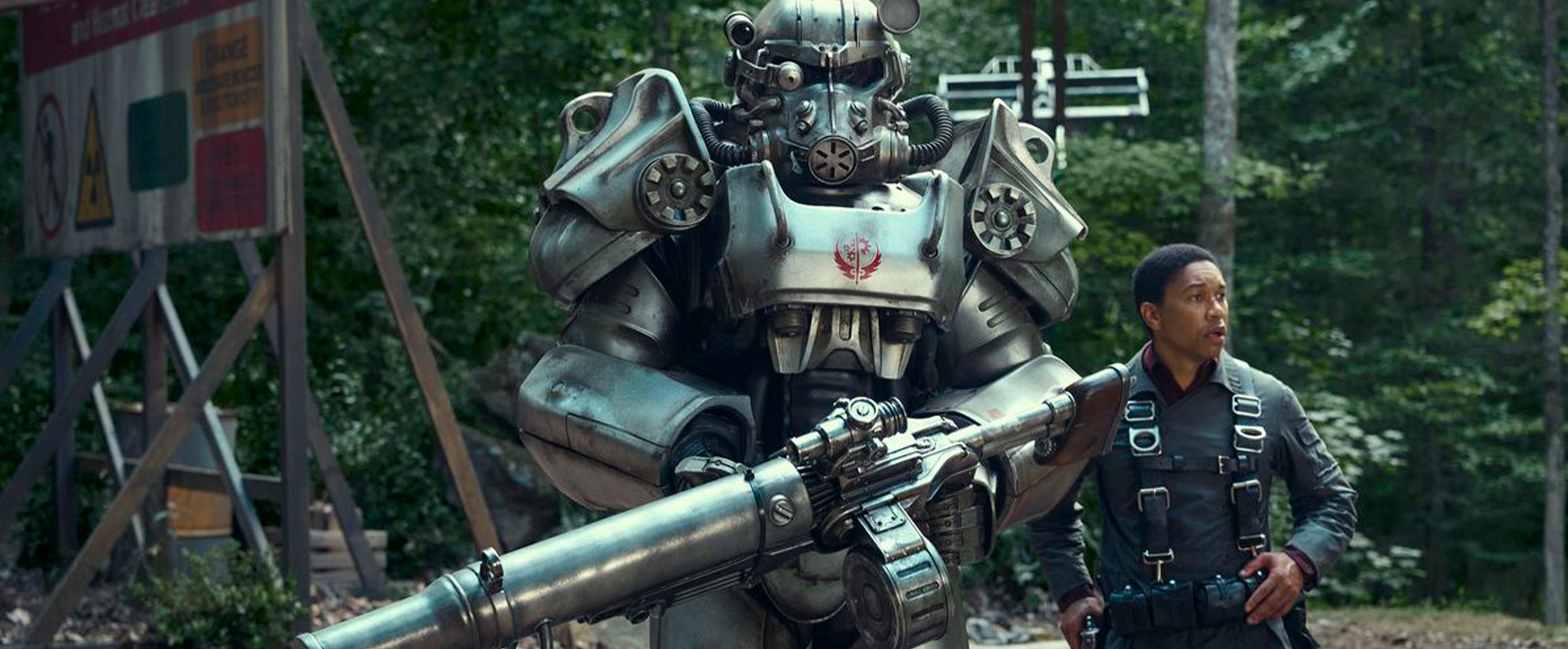 A man in a bulletproof vest stands next to a heavily armed, armoured robot