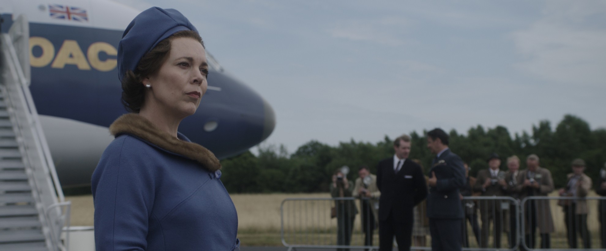 Olivia Colman as Queen Elizabeth the second, stepping off a plane in a 1960's setting and outfit