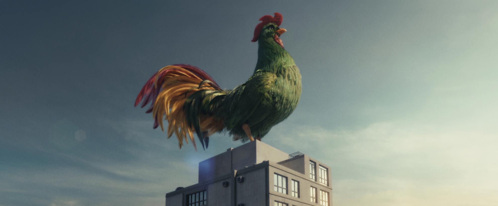 A large green CGI rooster sits on top of a tall urban building