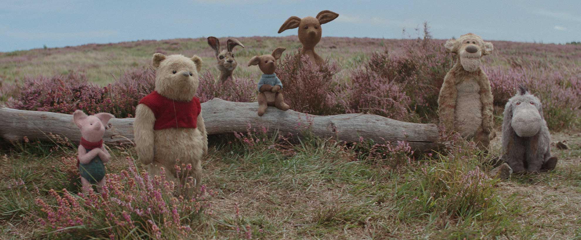 CGI Winnie the Pooh and friends sit on a log.
