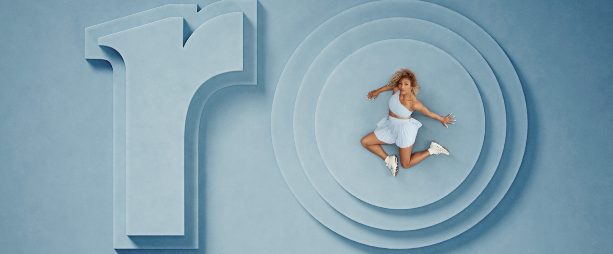 Serena Williams sits on a blue set with set pieces that say ro. She sits on the O