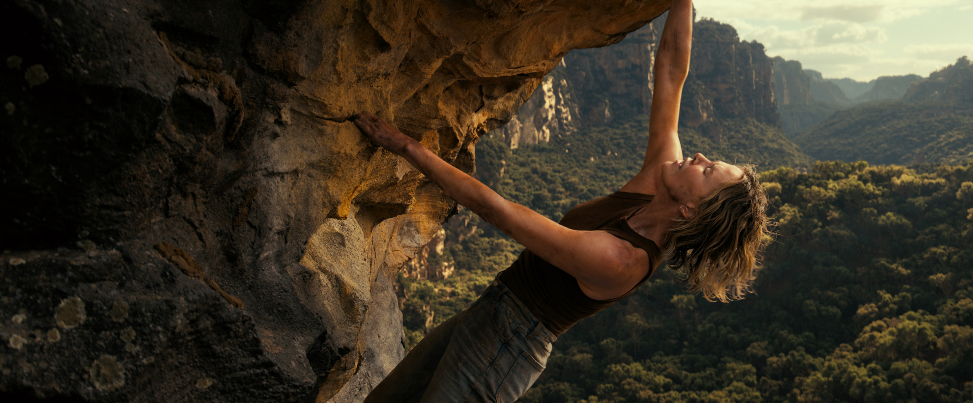 A still from Apex showing Sasha (played by Charlize Theron) climbing a rock face high above an Australian gorge