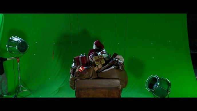 back shot of santa claus on a sleigh full of presents in front of a green screen