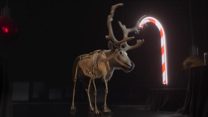 an animated reindeer that is see through. you can see the reindeer skeleton. there is a large glowing christmas candy cane touching the right ride of the antler