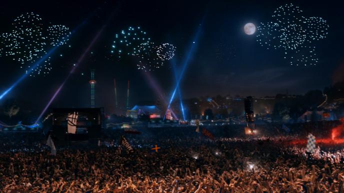a concert crowd with fireworks and the moon in the night sky