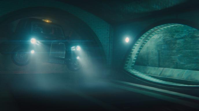 a british black cab with its headlights on driving underwater inside of a tunnel