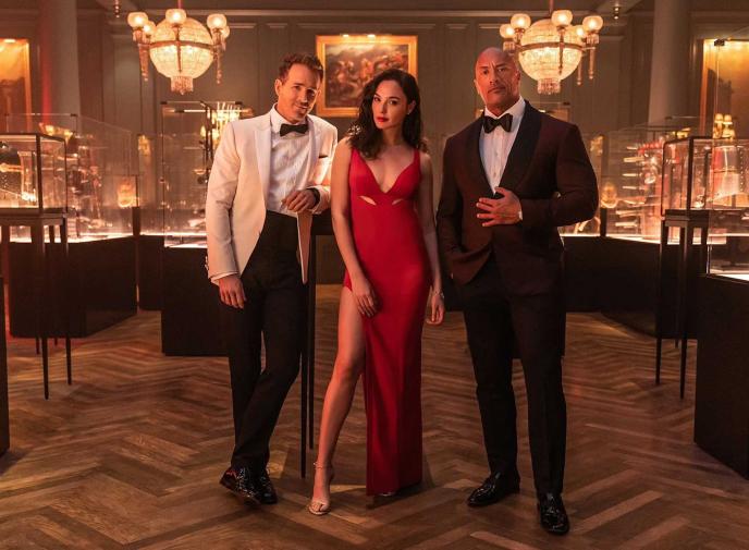 three red notice characters wearing black tie wear standing in a fancy bar