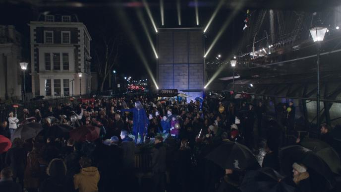 a crowd of people watching a magician that is in a spotlight