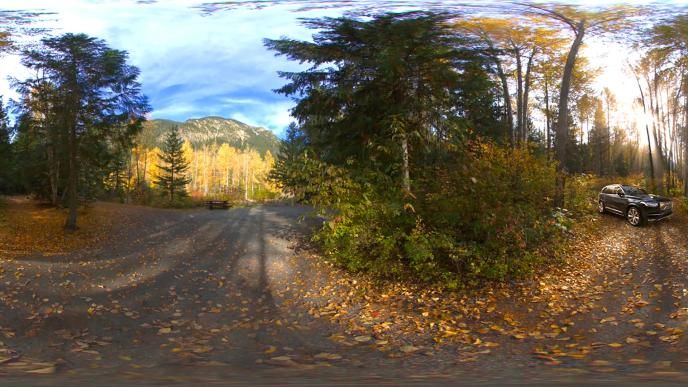 virtual reality 360 degree view of mountainous scenic views. there is a volvo xc90 car parked on the right as sun beams down the image