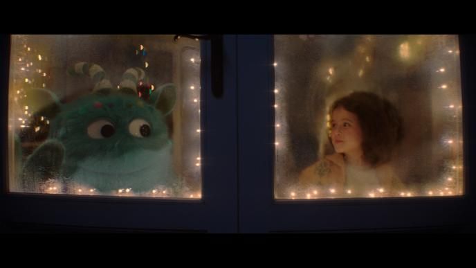 outside perspective of a window. iggy and a little girl looking at each other. there are fairy lights surrounding the window sill inside