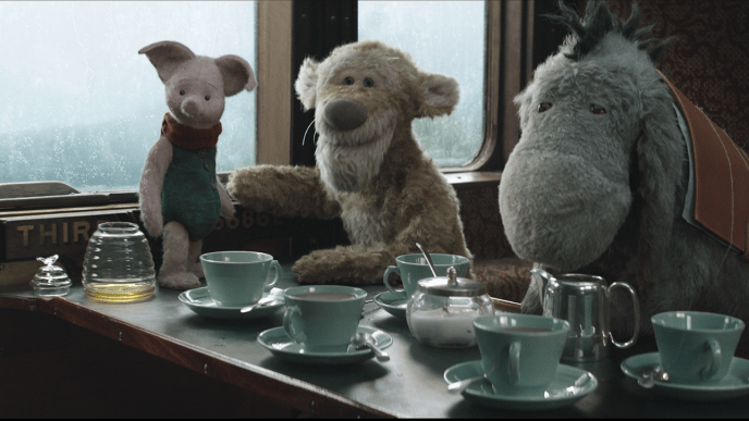 Piglet, Tigger, and Eeyore sit in a train carriage, with the table set for tea