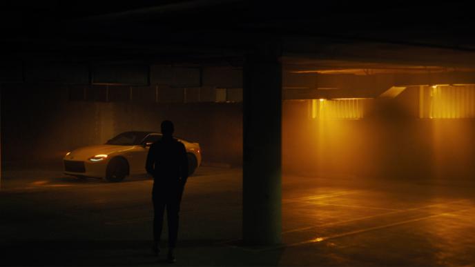 The silhouette of a man as he walks to a Nissan Z in a dark parking garage