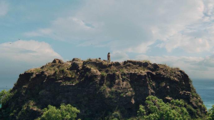 Catherine Lagaʻaia as Moana standing on top of a large mountain, looking out over the ocean