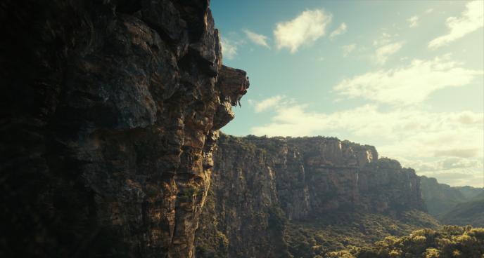 Sasha, played by Charlize Theron, hanging from the cliff edge high above an Australian gorge
