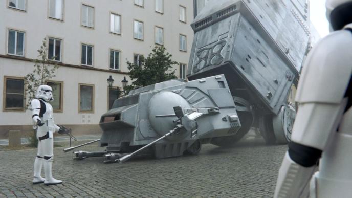 two star wars stormtroopers onlooking a fallen AT-AT. the one closest to it has their arms up in disbelief