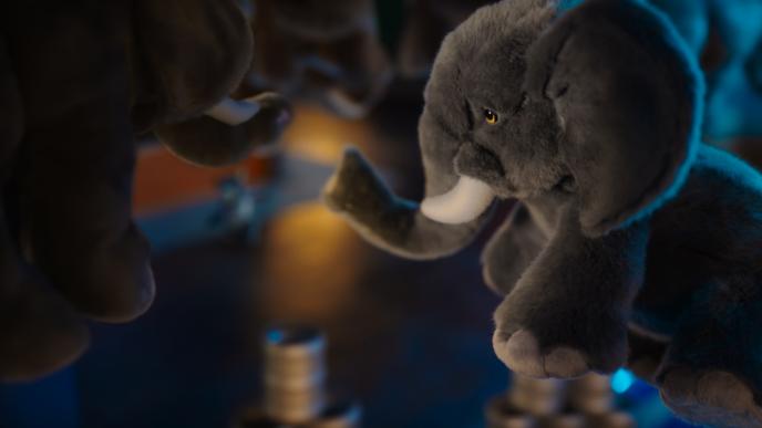 a couple of stuffed elephant teddies hanging up. one of them looks defeated