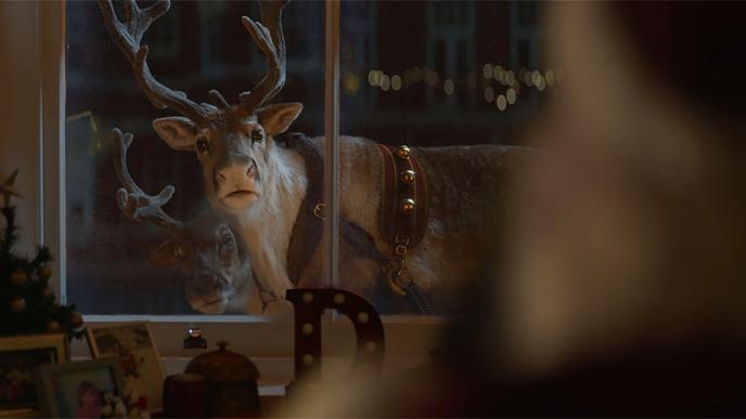 a curious reindeer peeking into a living room from the outside