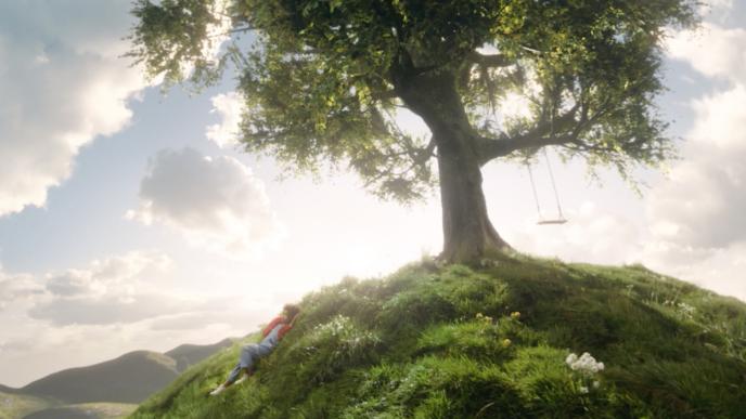 tranquil animated environment of a child laying near a tree that has a swing attached to it. there are soft clouds and warm sunlight in the sky