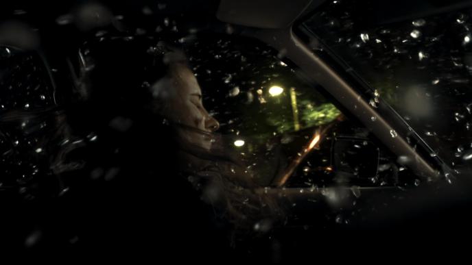 interior view of a car crash with a person closing their eyes as glass shatters around them
