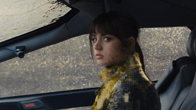 actress ana de armas as joi sitting in the passenger seat as she starts becoming pixelated