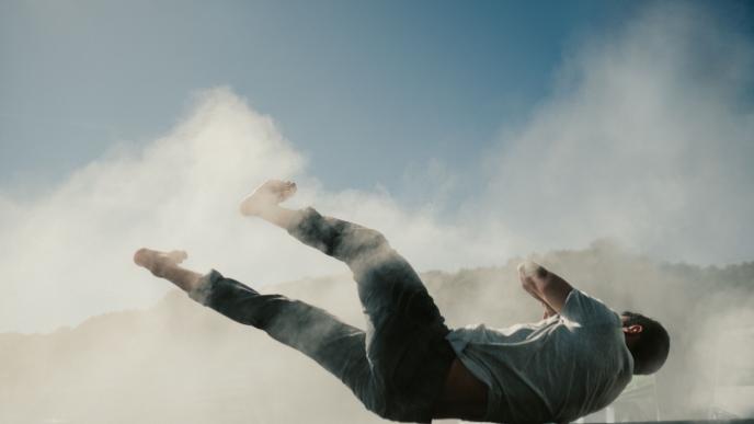 a person falling down on their back. dust surrounds them