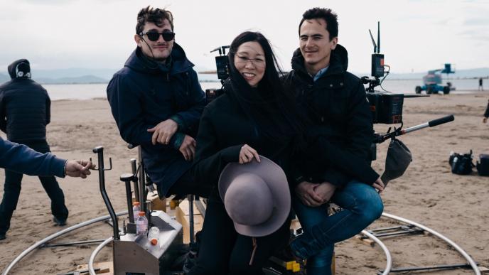 director anh vu sitting on a beach with filmmakers and film crew