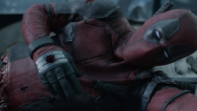 deadpool laying on the ground with a ripped torso and a shot hand