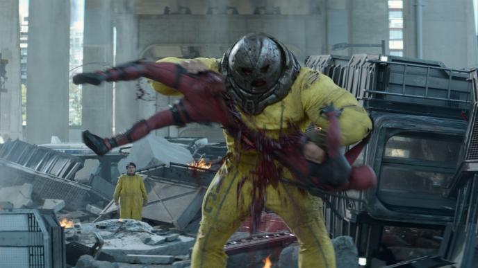 juggernaut ripping deadpool in half amidst rubble as accomplice watches in the background