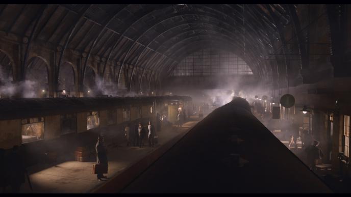 perspective from the roof of a train inside of a train station overlooking trains and passengers