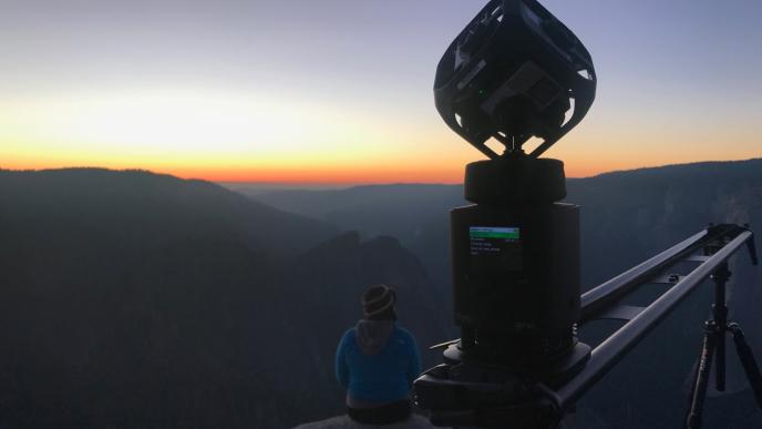 film crew and camera sitting on top of the el capitan cliff overlooking the yosemite national park during sunset