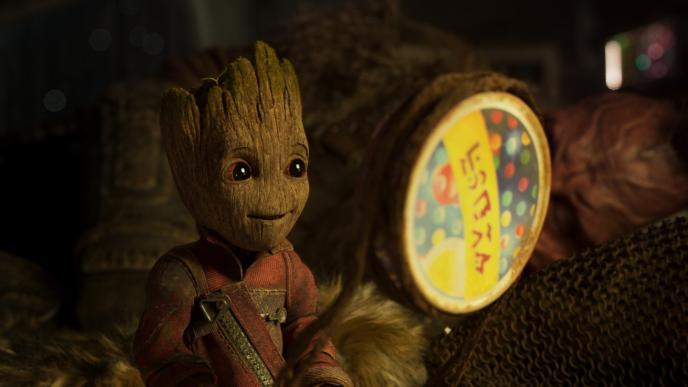 baby groot sitting down and happily looking towards the left