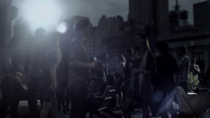 a crowd gatheredat a rooftop party. buildings surround the rooftop
