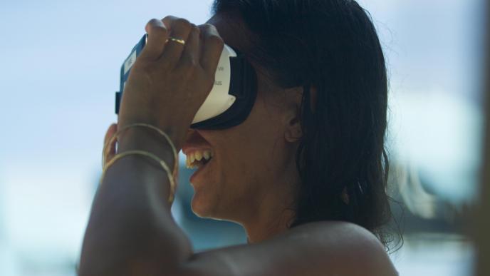 side view of a woman holding up a vr headset to her face