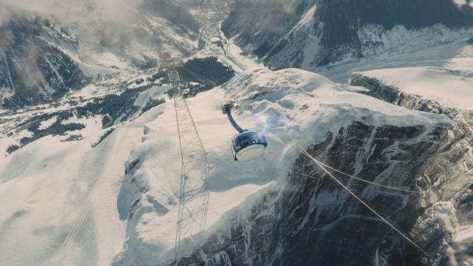 aerial view of a cable car and tower on a snowy mountain