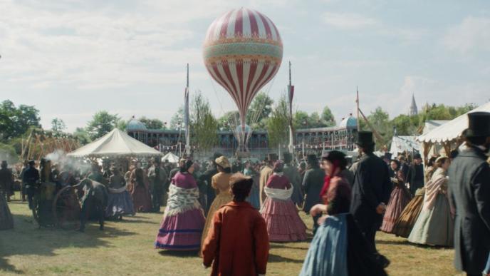 19th century fun fair bustling with people with a hot air balloon in the centre