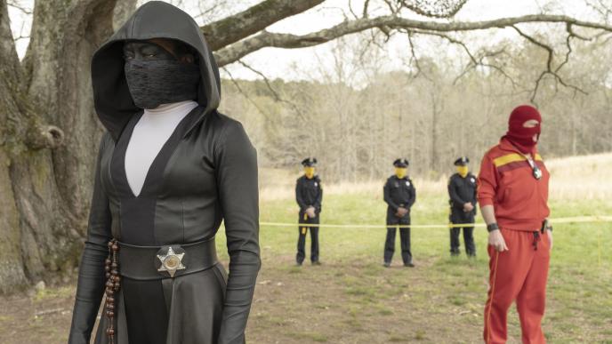 watchmen characters standing in front of a tree as three police officers stand in the back
