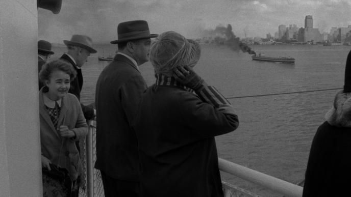 six people standing on a boat watching the new york city skyline on the sea