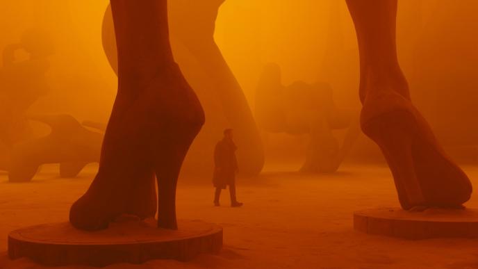 agent k walking through giant sculptures in an orange atmosphere