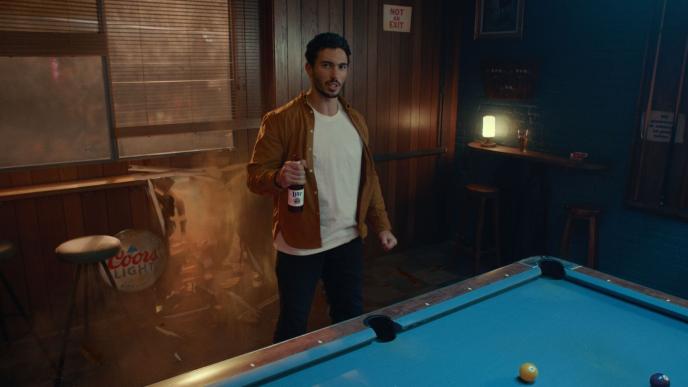 A man holding a beer next to a pool table